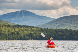 Woman kayaking on freshwater lake in the mountains in nature in a natural setting Chittenden Reservoir, Vermont, USA