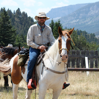 picture of Phil riding horse with mountains in background