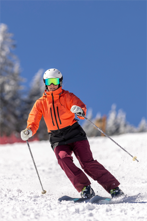 Woman snow skiing on a sunny winter day with fresh white snowy on the trees wearing a helmet and goggles. Thrill and excitement on the slopes of Okemo, Vermont, USA.